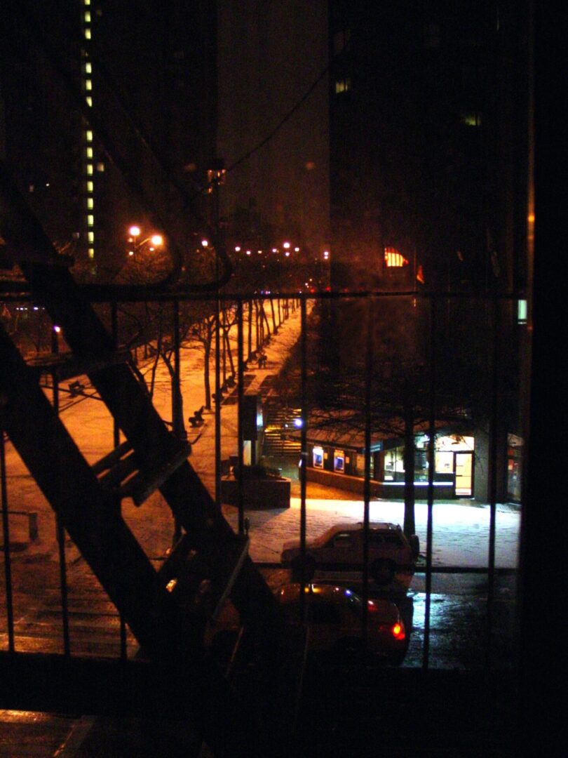 Nighttime view of a street through a window with a grid.