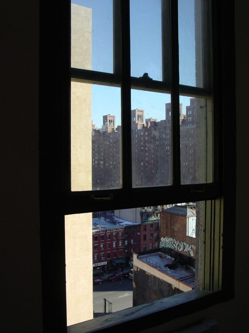 City buildings viewed through a window frame during daylight.