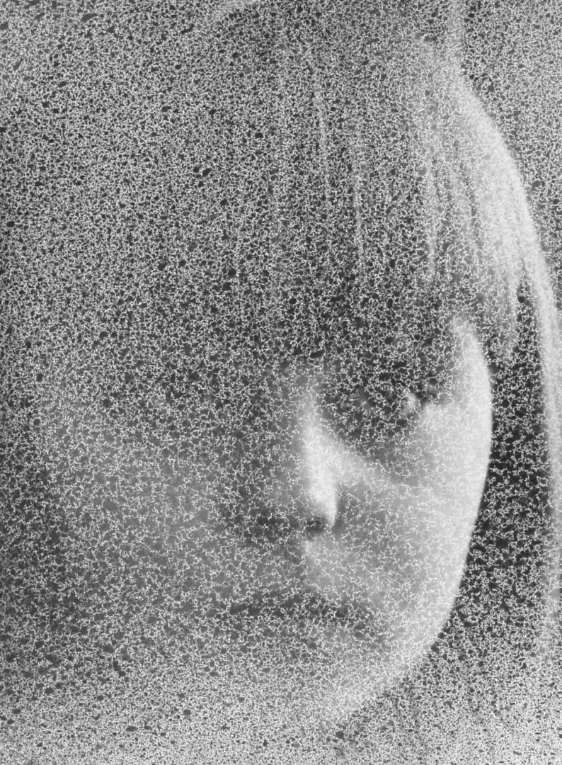 Grainy black-and-white close-up of a person's face with bangs.