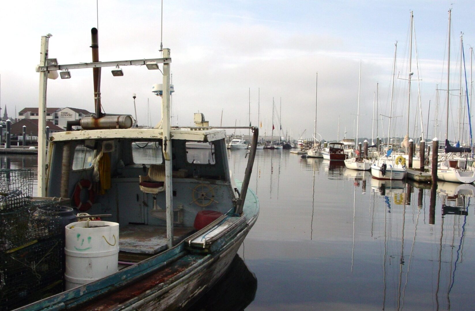 Old fishing boat docked in a calm harbor with other boats.