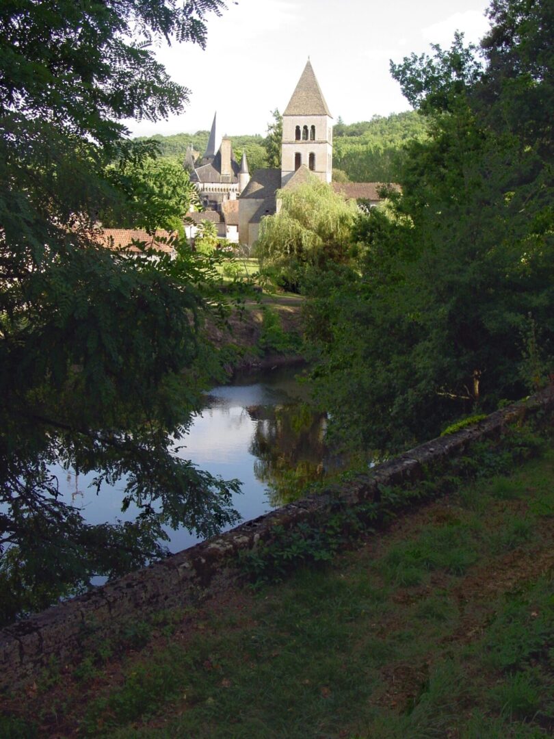A serene river scene with a church tower in the background.