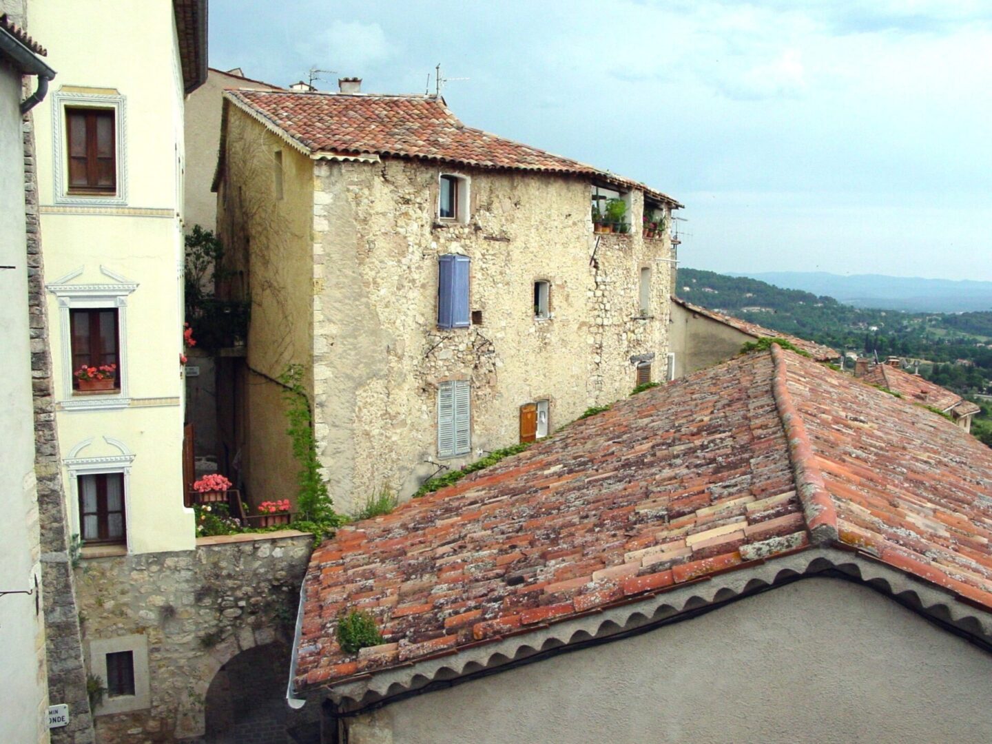 Old stone building with red-tiled roofs in a rural setting.