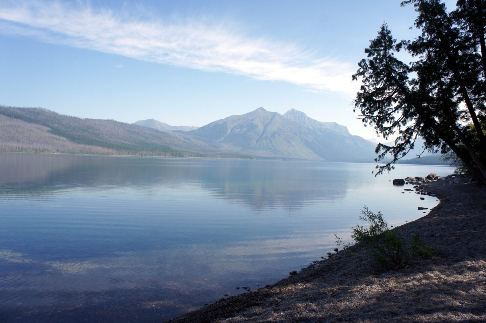Serene lake with mountains under a clear blue sky.