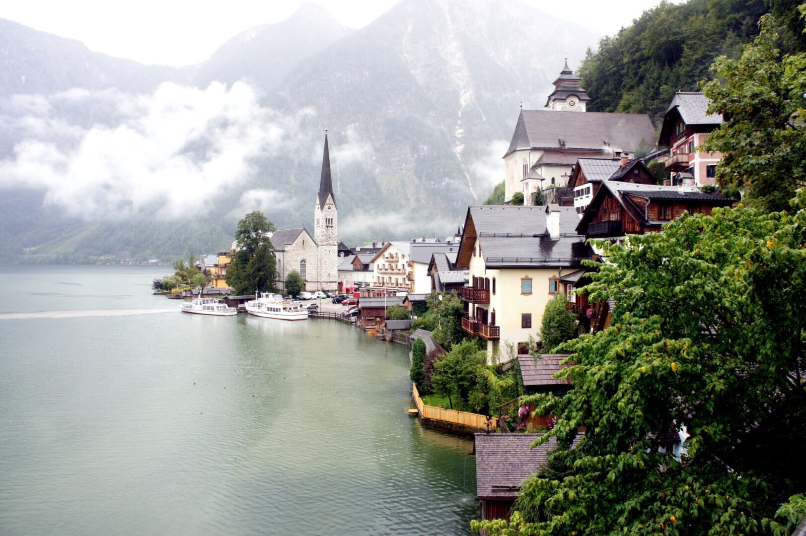 Scenic lakeside village with mountains and mist in the background.