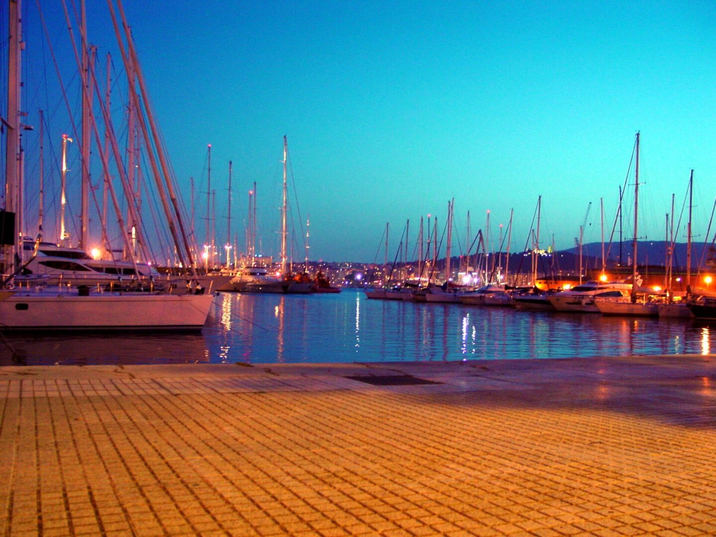 Sailboats docked at a calm marina during twilight.