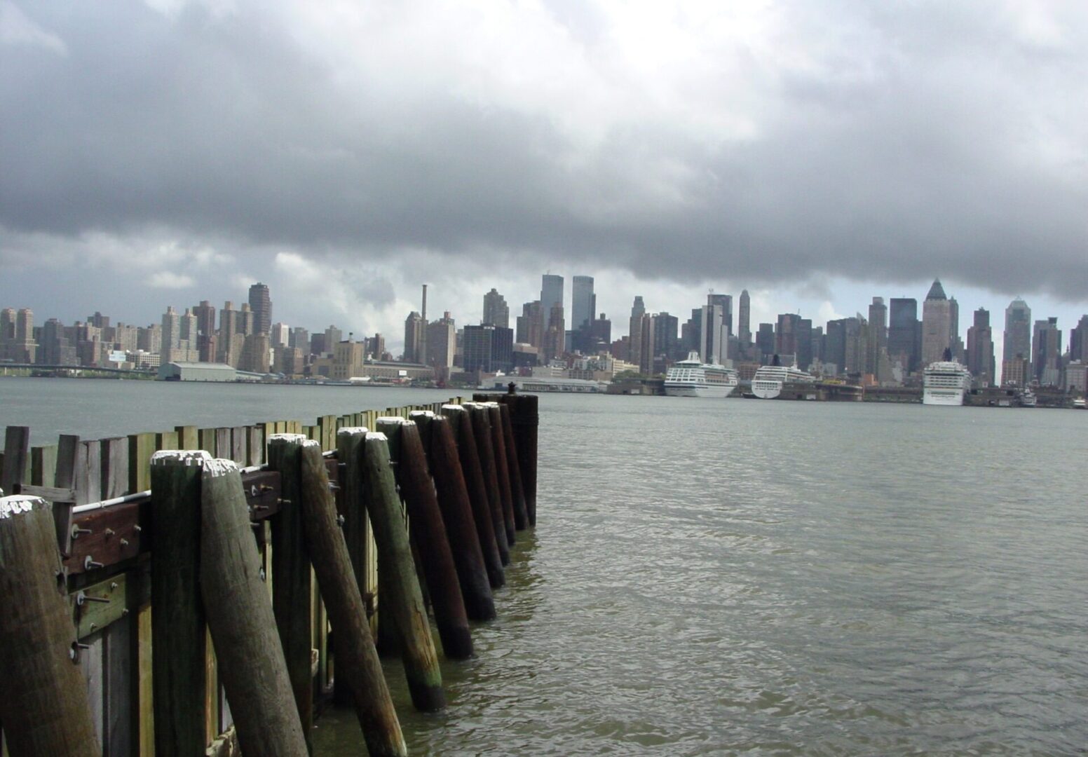 City skyline with wooden posts in cloudy weather by the water.