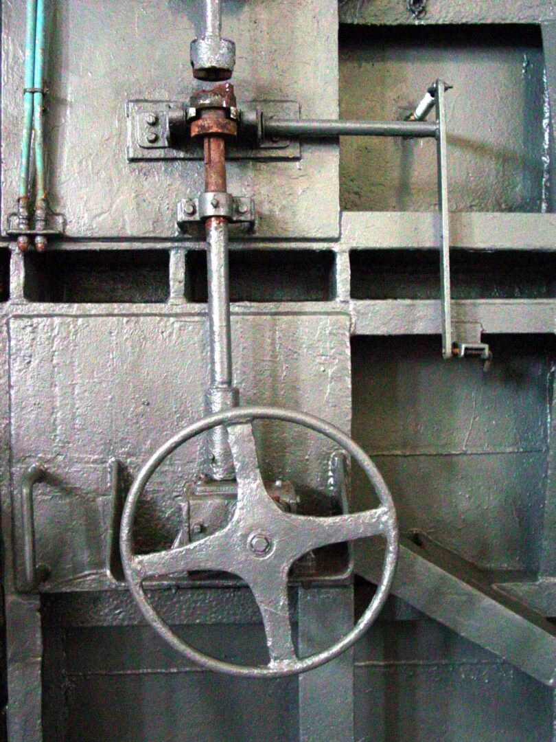 Close-up of a metal valve wheel in an industrial setting.