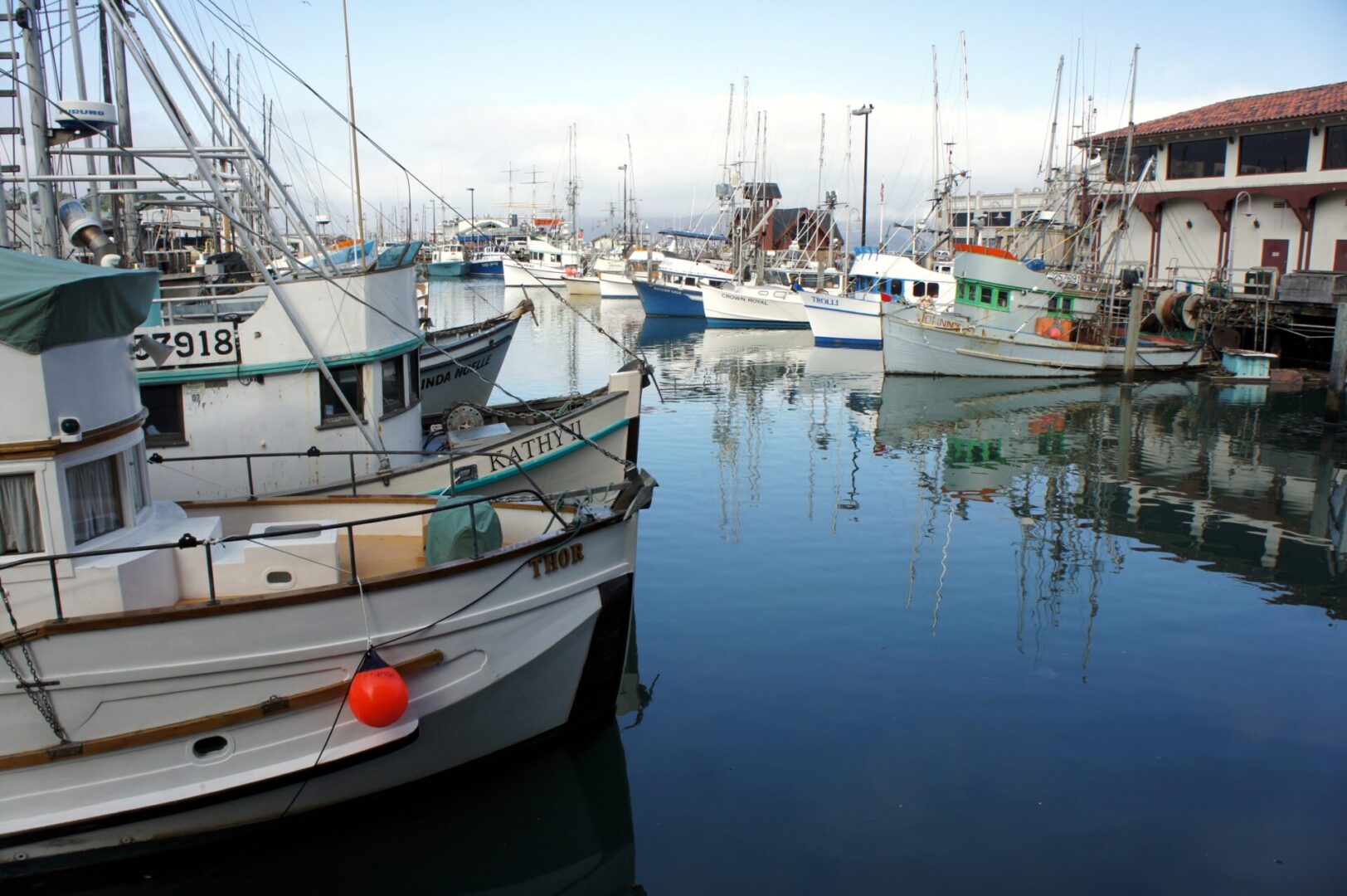 Boats docked peacefully in a calm harbor under a clear sky.