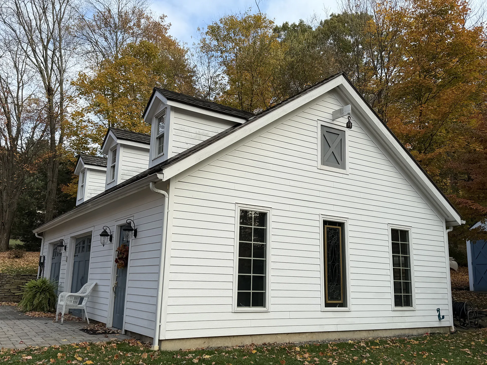 A white house with tall windows surrounded by autumn trees.