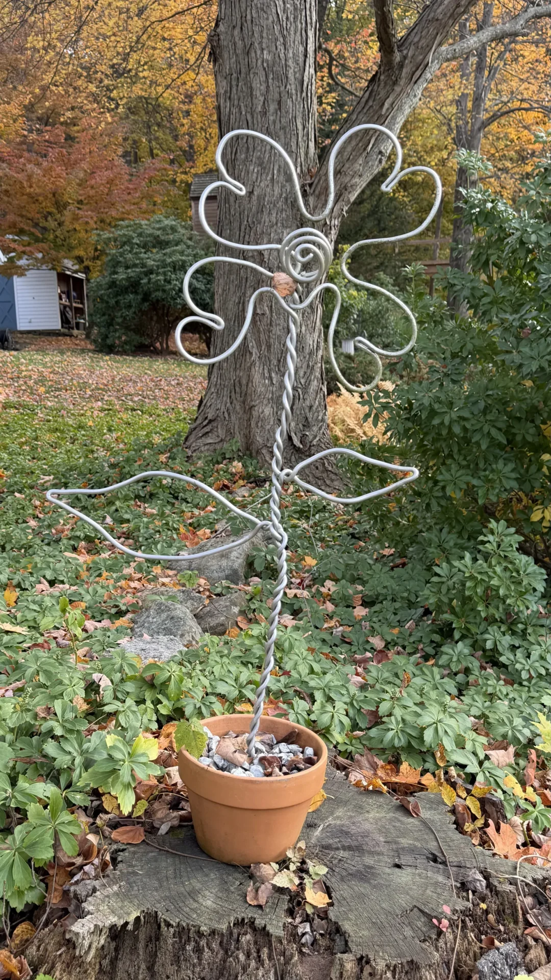 Abstract metal garden sculpture with flowing shapes near a tree.
