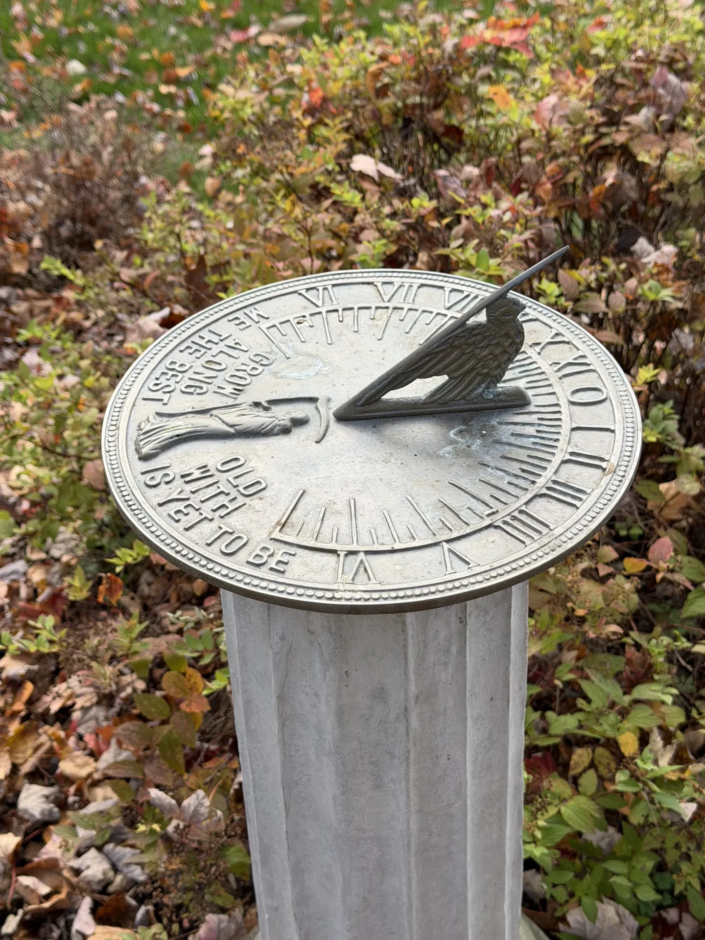 A sundial showing time in a leafy outdoor setting.