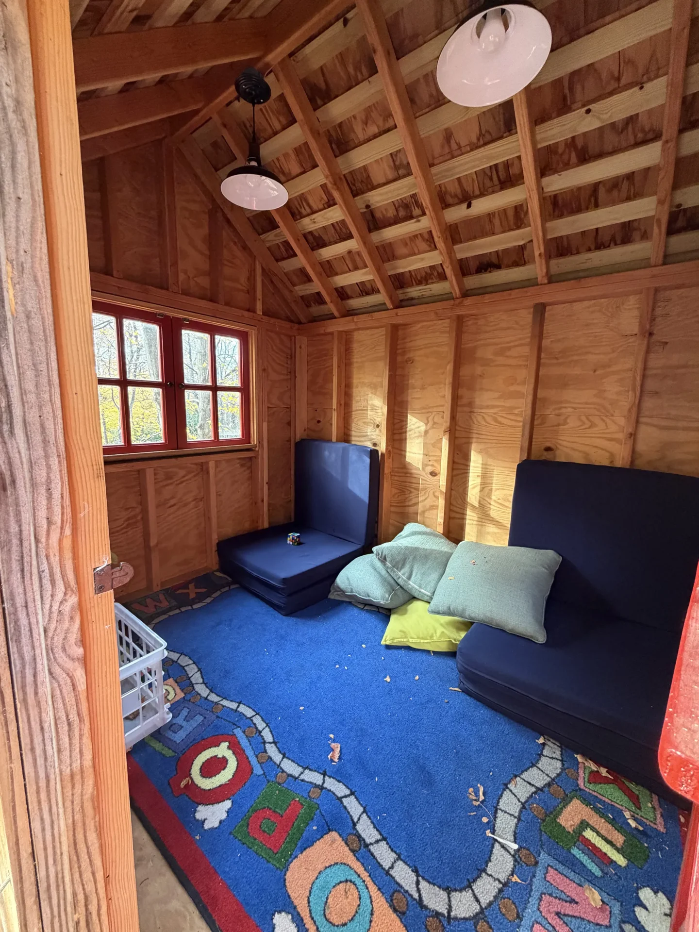 Cozy wooden room with cushions and a colorful rug.