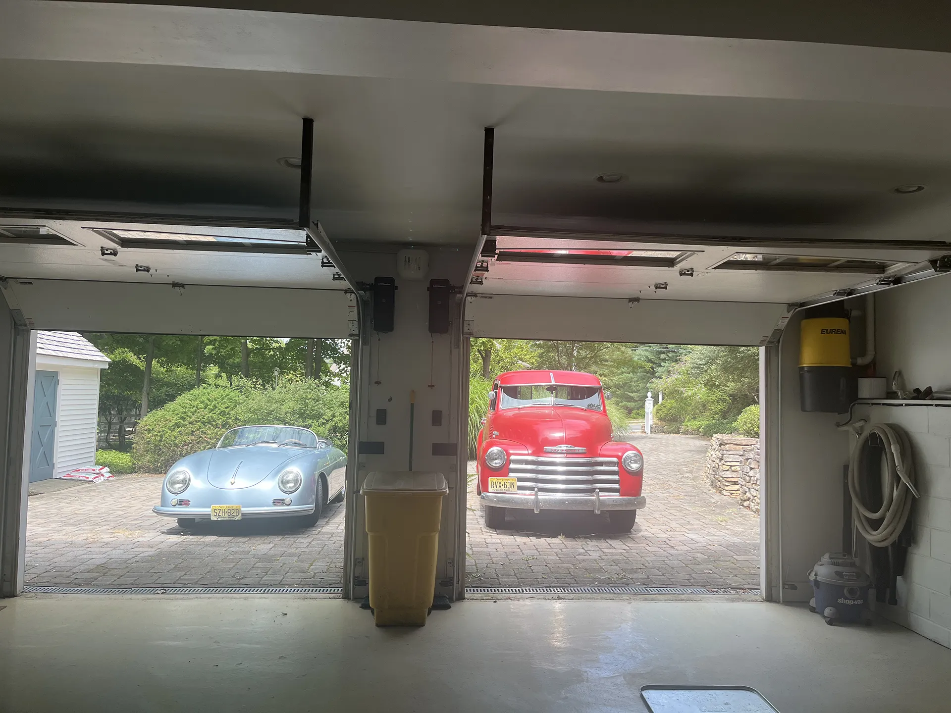 Red truck and silver car parked outside a garage entrance.