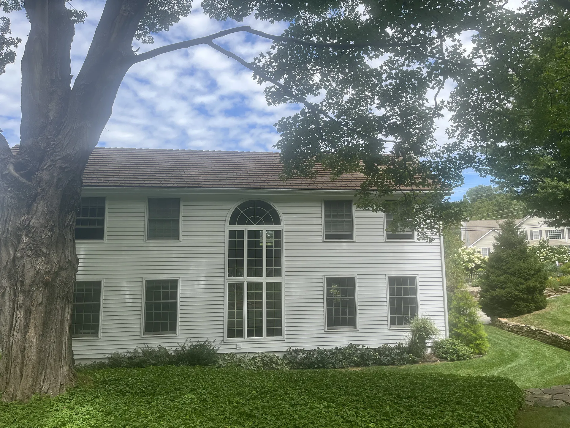 White two-story house with large arched windows and a green lawn.