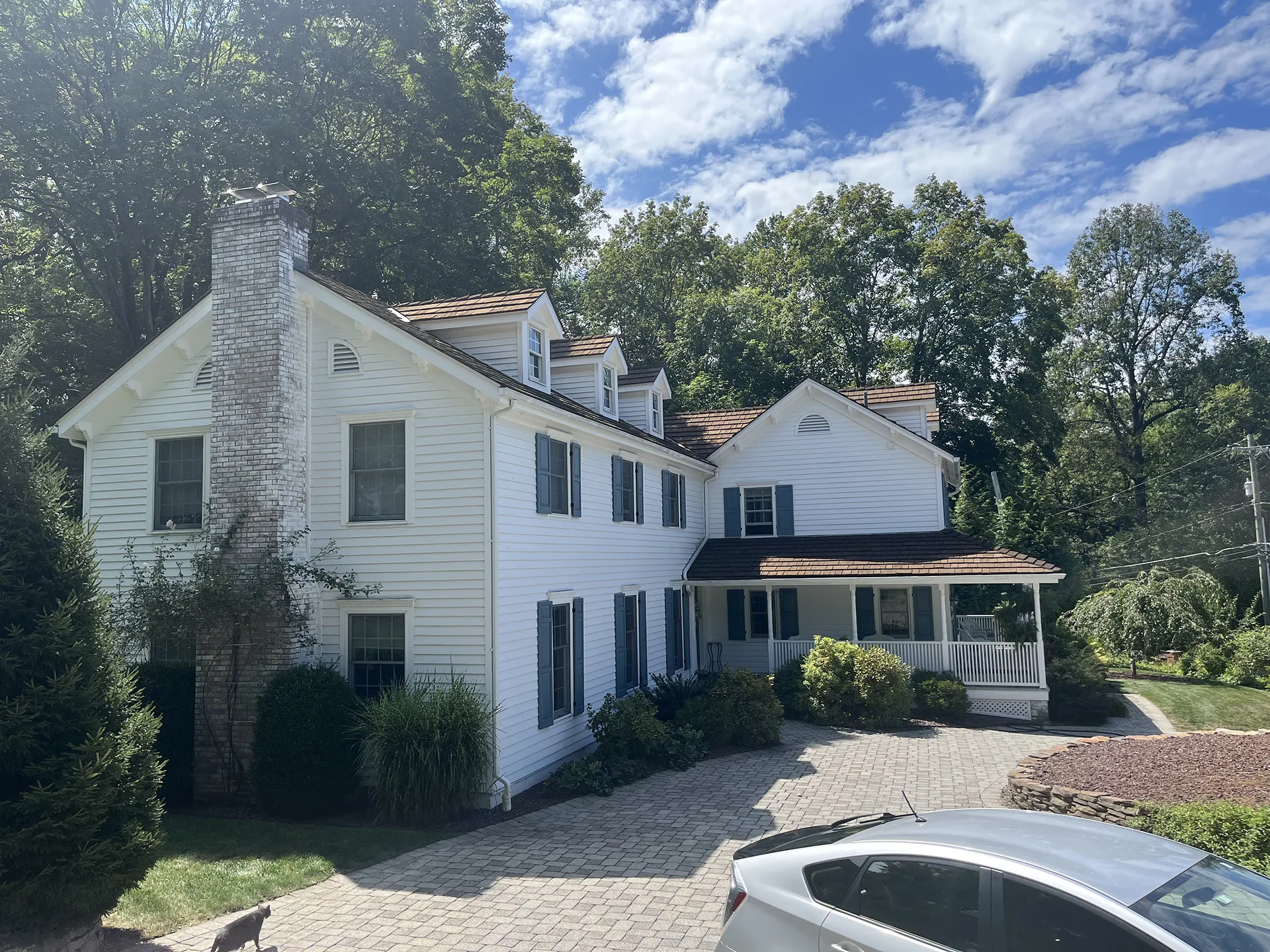 Large white house with multiple chimneys and surrounding greenery.