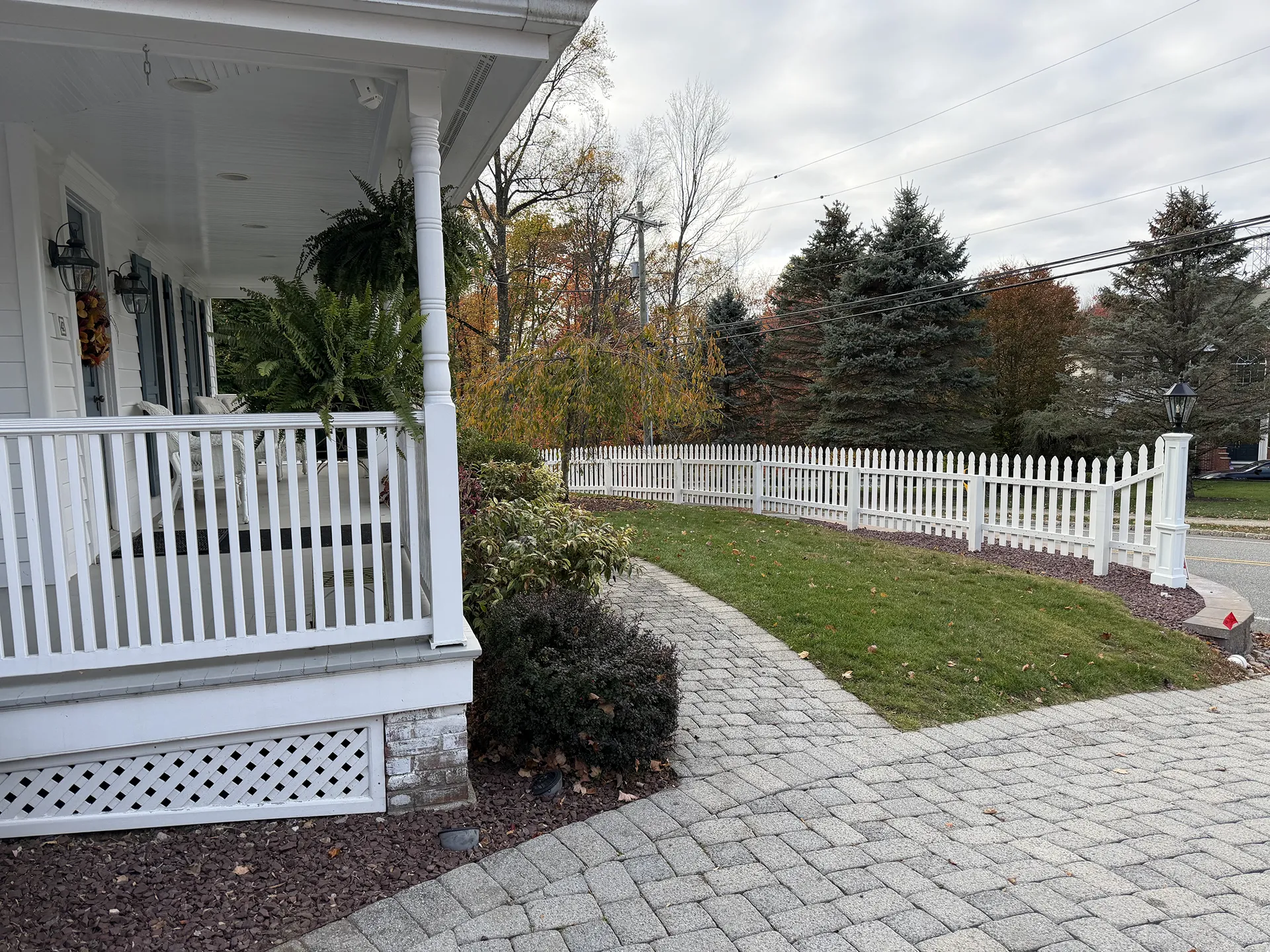 A front porch with white railings and a paved walkway leading to a small garden.