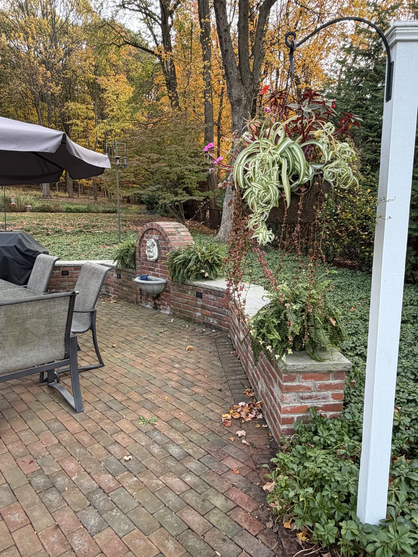Cozy outdoor seating area with brick patio and autumn foliage.