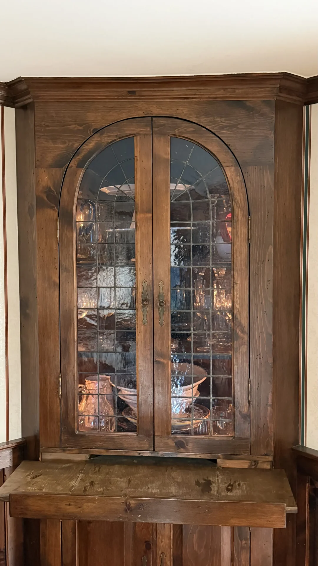 Wooden cabinet with glass doors showcasing kitchenware.