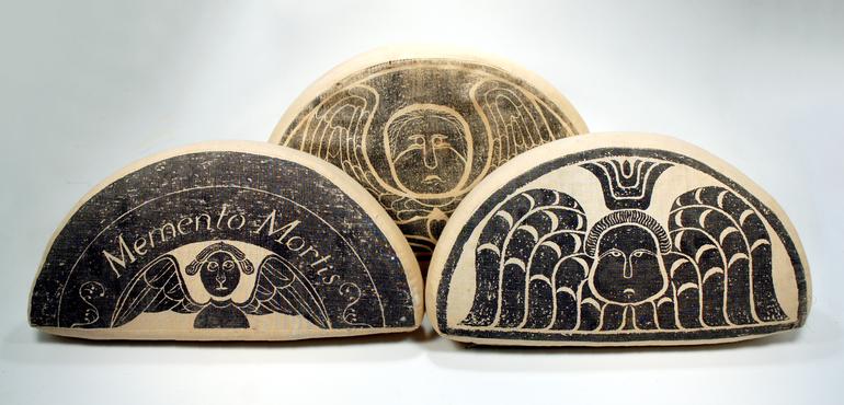 Three wooden cheese wedges with intricate black designs.