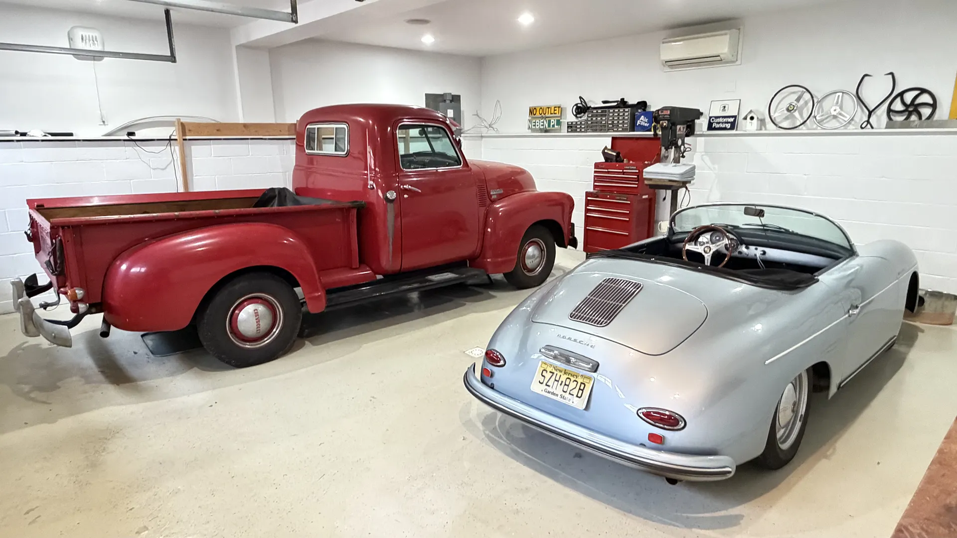 Classic red pickup and silver vintage sports car parked indoors.