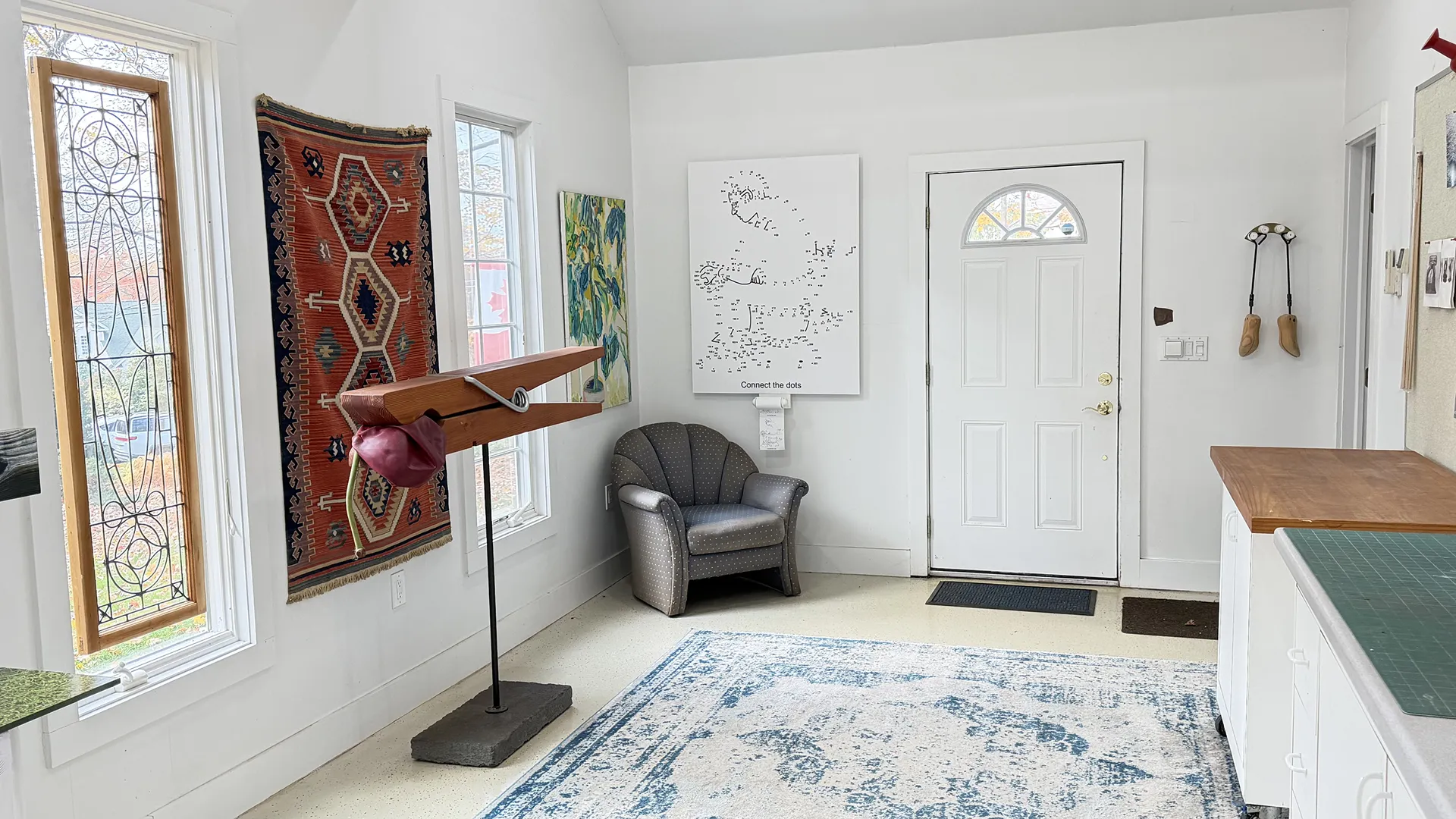 Cozy reading nook with armchair, rug, and decorative wall art near a front door.