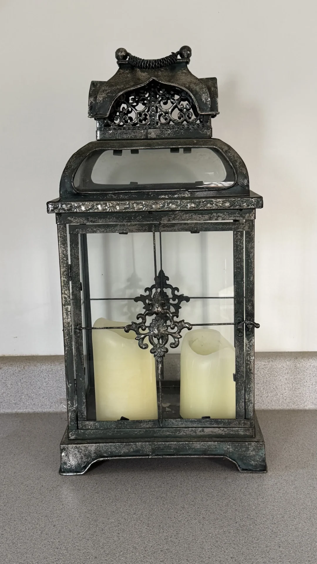 A vintage lantern with two white candles inside.