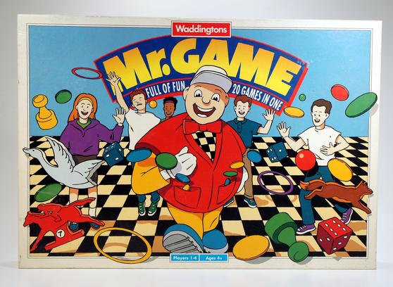 Colorful board game box featuring cartoon characters and a cheerful man in a red jacket.