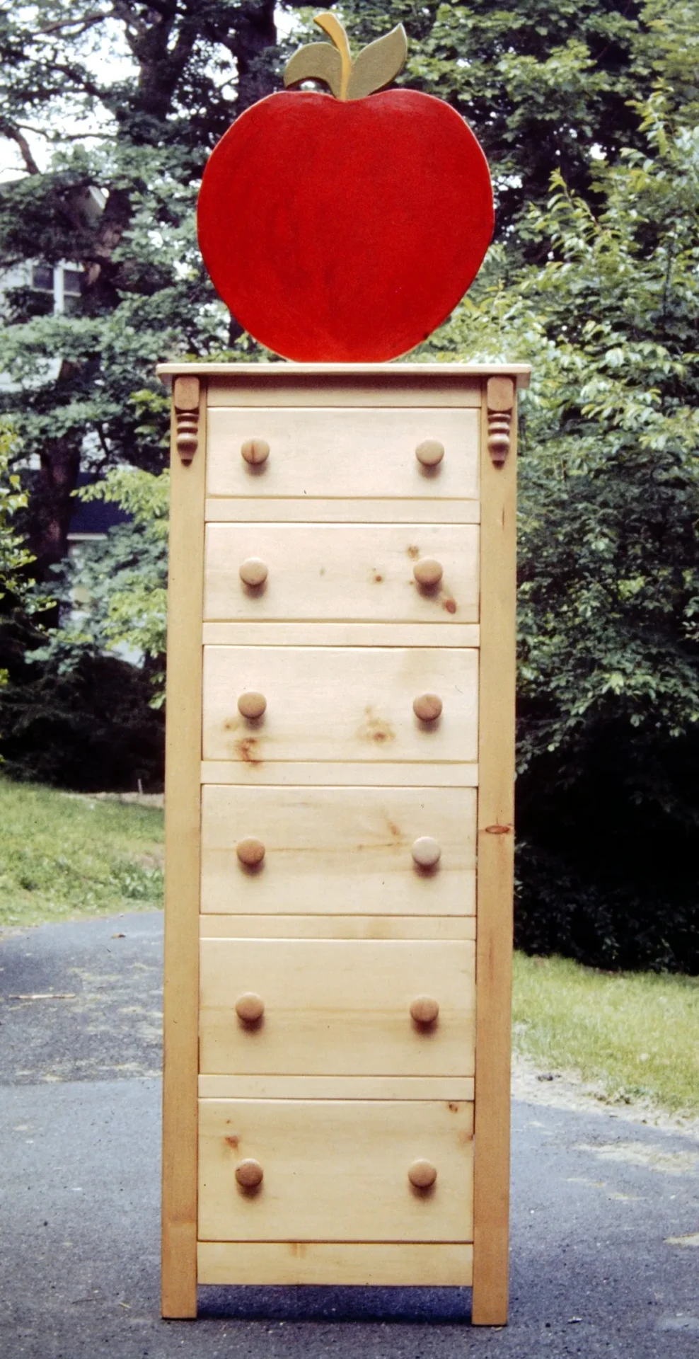 Tall wooden dresser with multiple drawers outdoors.