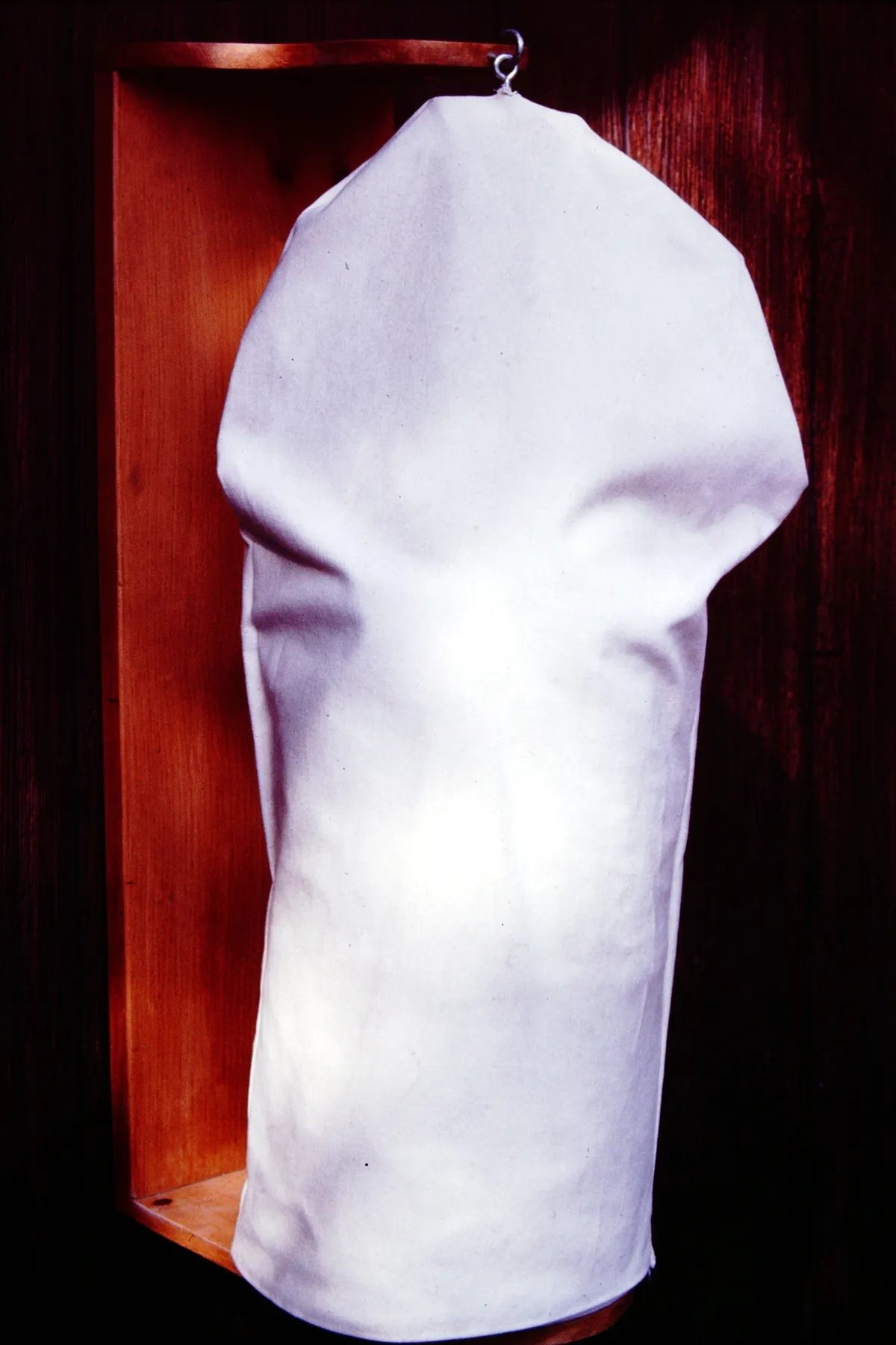 A white cloth draped over an object against a dark background.