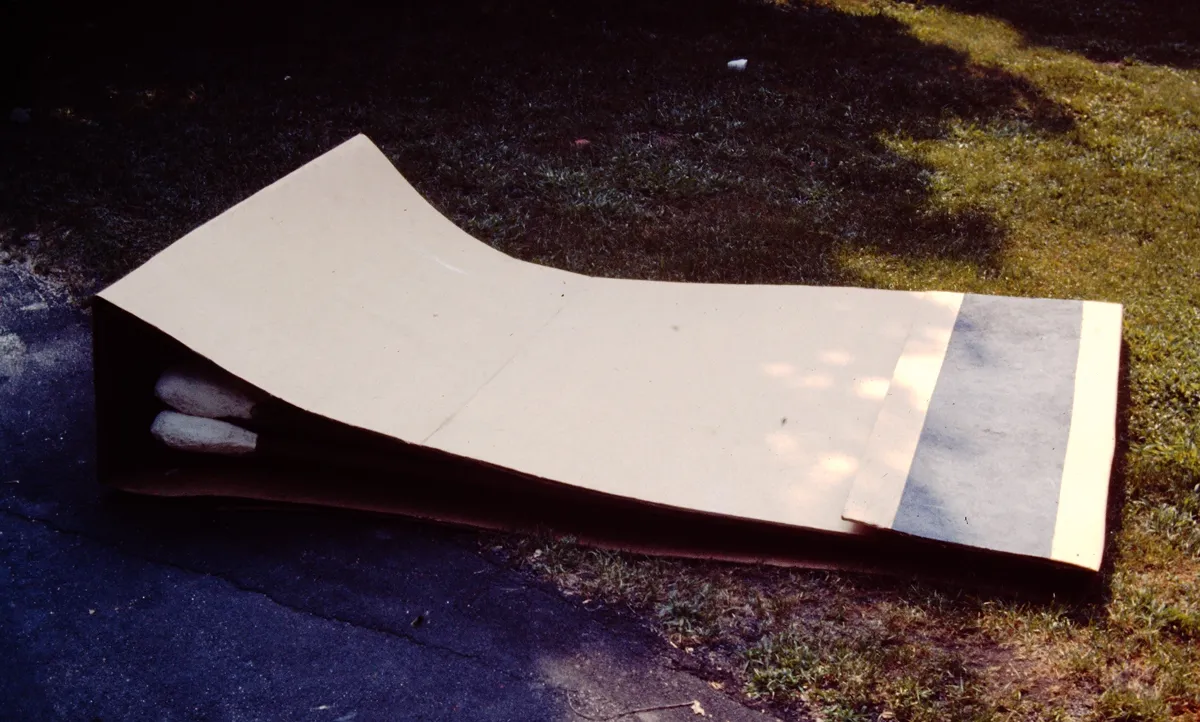 A large white tarp or sheet partially spread on the grass outdoors.