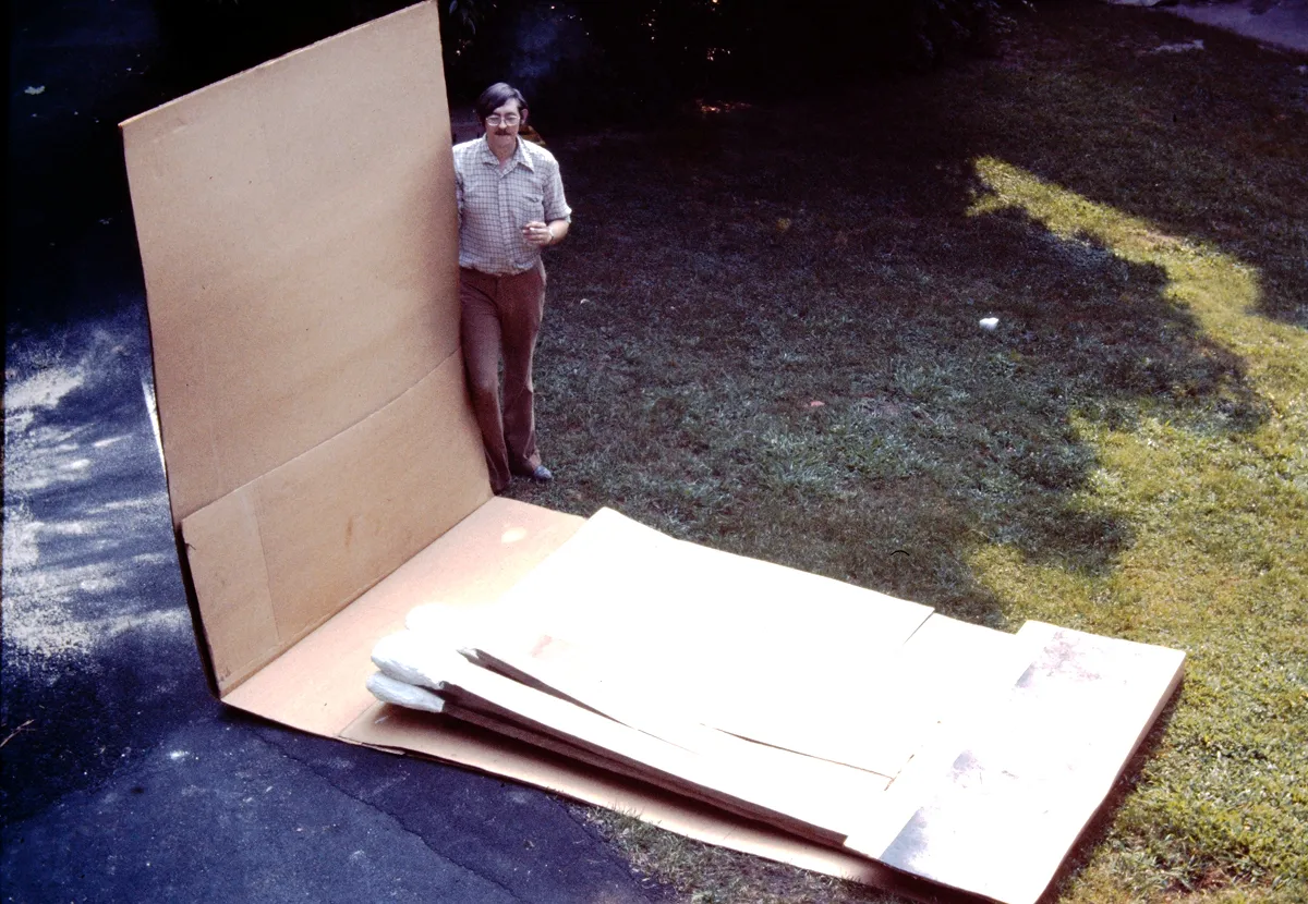 Man standing near large cardboard boxes outdoors.