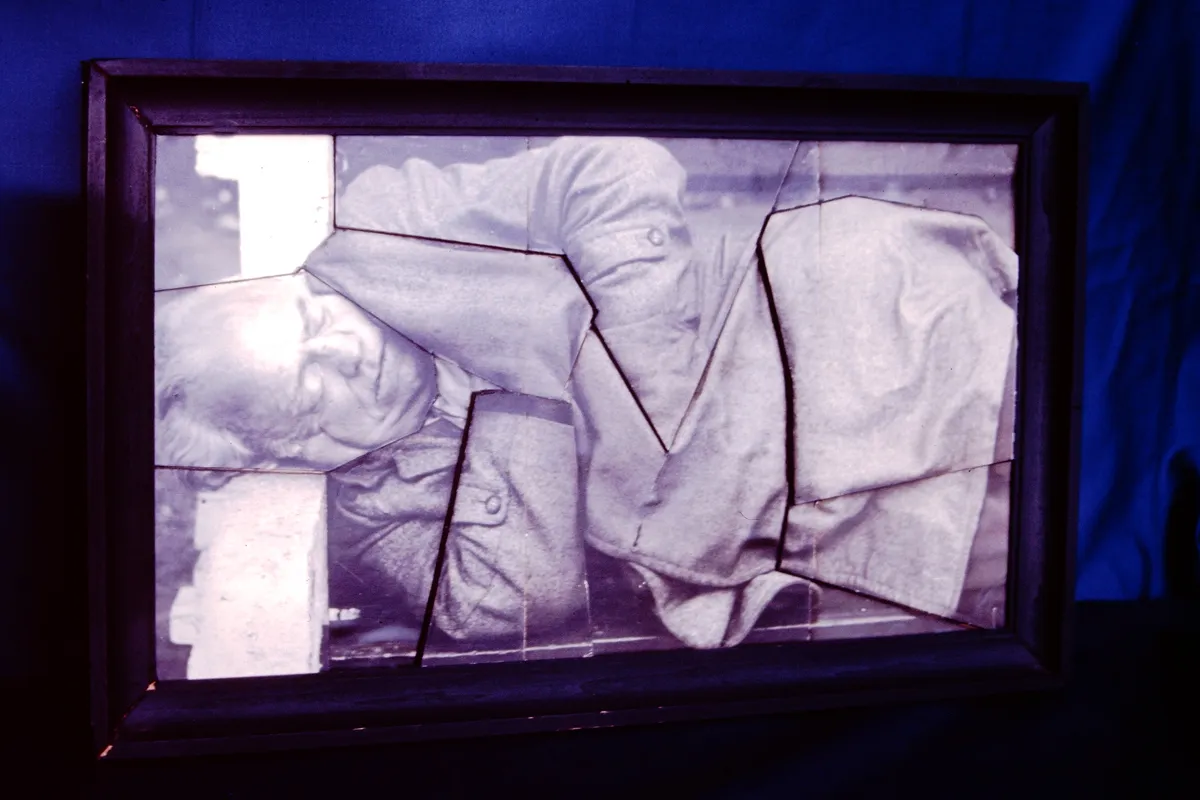 Ancient mummified figure wrapped in cloth inside a glass case.