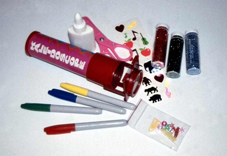 Craft supplies including paint tubes, markers, and glitter for creative projects.