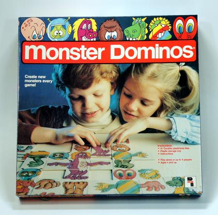 Two children playing with colorful monster-themed dominoes.