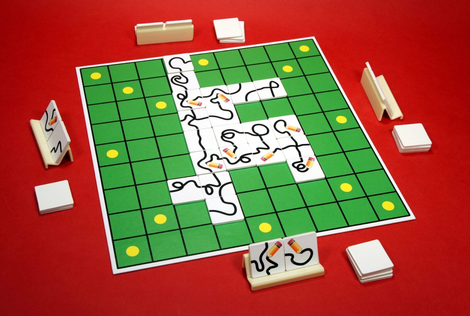 A board game with puzzle pieces and green grid tiles on a red table.