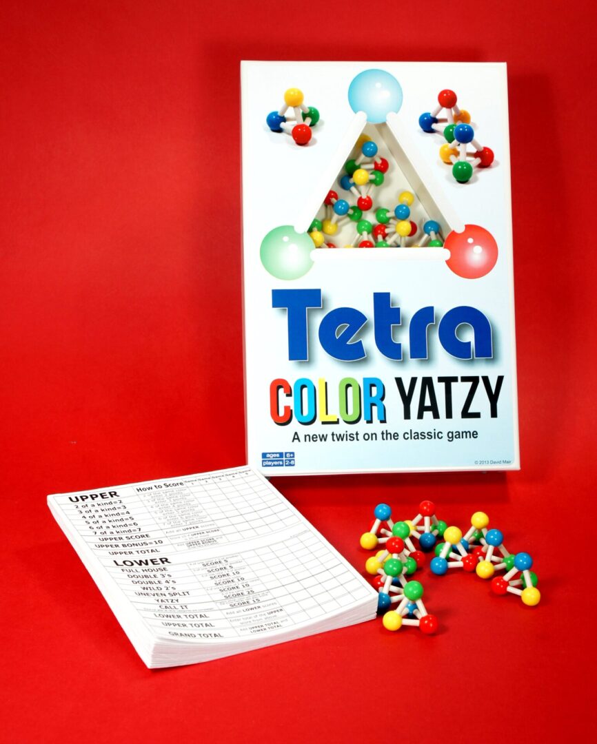 Tetra Color Yatzy game set with colorful pieces and instructions on a vibrant red background.