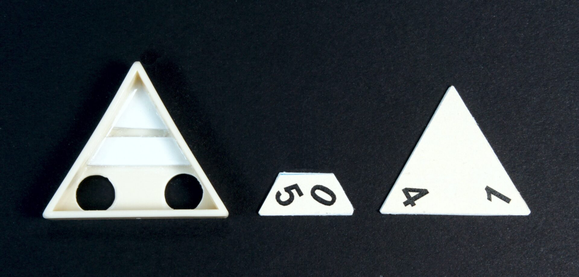 Close-up of white triangular game pieces with black numbers and a black background.