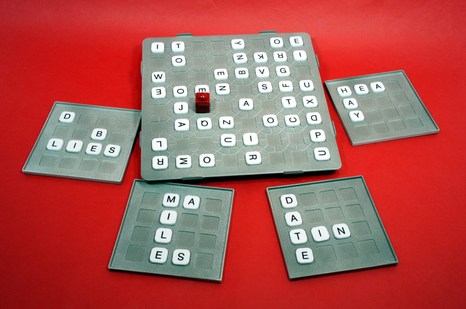 Multiple wooden Sudoku boards with lettered tiles on a red background.