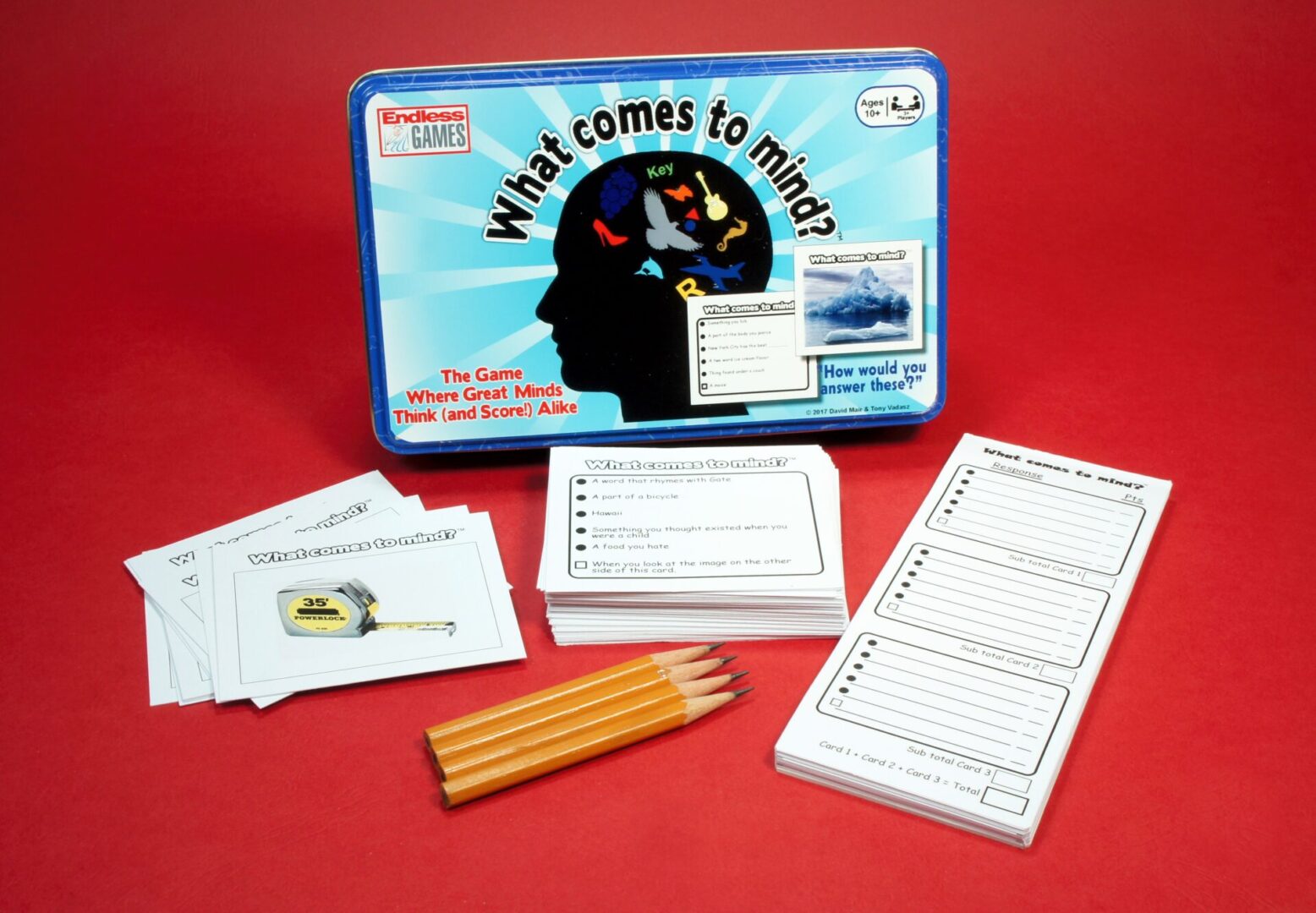 A board game titled 'What Comes to Mind' with cards, pencils, and score sheets.